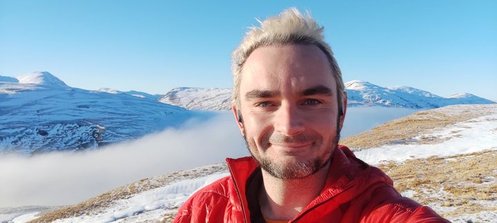 A photo of me, Karn, on top of a snowy mountain with a cloud inversion behind me.