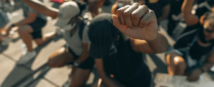 A crowd of people leaning on the ground with one knee bent, fists clenched and raised in the air